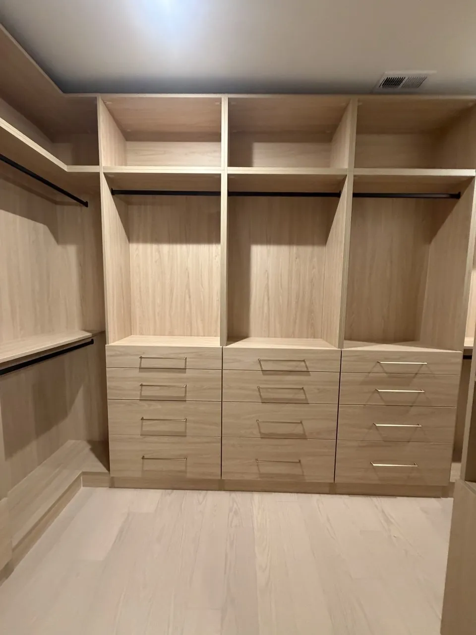 Walk-in closet with a full-width drawer bank and open hanging sections