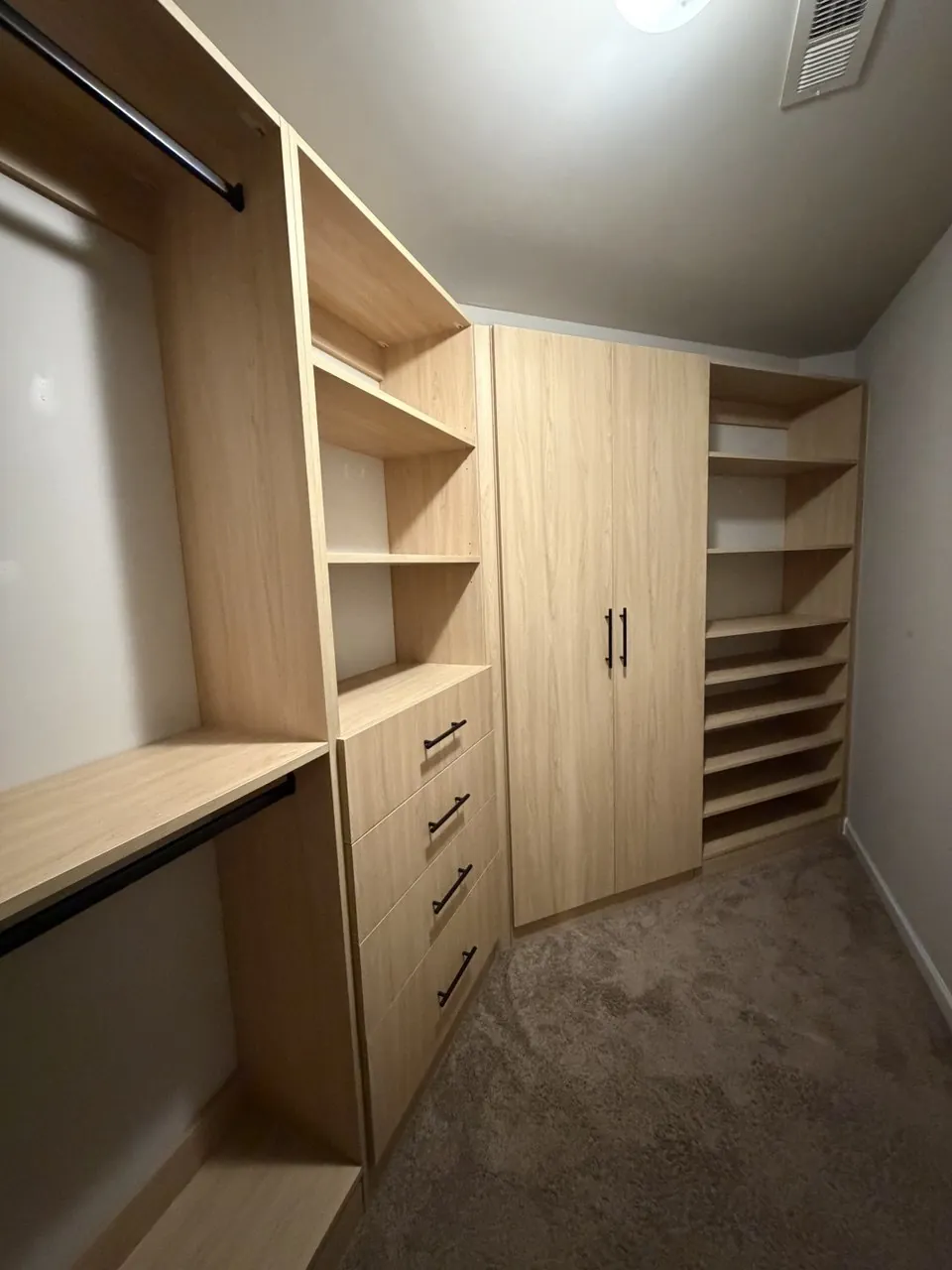 Walk-in closet with angled shoe shelving and a tall storage cabinet
